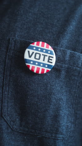 Anonymous-African-American-man-puts-on-badge-with-USA-flag-logo-and-inscription-I-Voted.-US-citizen-at-polling-station-during-elections.-National-Election-Day-in-United-States-of-America.-Close-up.