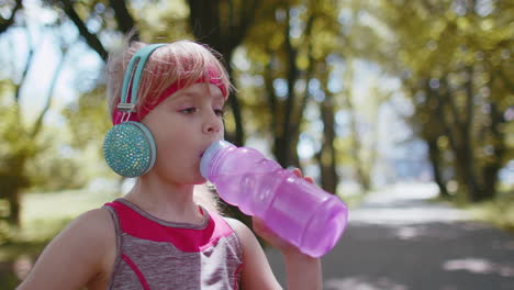 Athletic-fitness-sport-runner-child-girl-kid-drinking-water-from-bottle-after-training-exercising