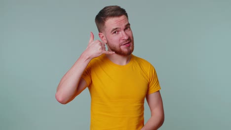 Cheerful-one-man-in-t-shirt-looking-at-camera-doing-phone-gesture-like-says-hey-you-call-me-back