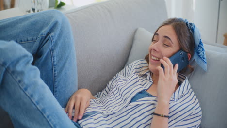Glückliche-Frau-Genießt-Telefongespräch-Auf-Dem-Sofa-Im-Wohnzimmer