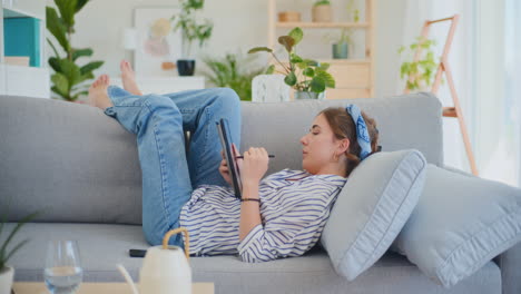 Happy-Woman-Enjoying-Social-Media-on-Sofa-with-Digital-Tablet