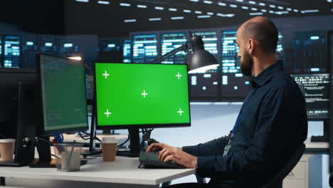 Man-typing-code-on-green-screen-computer-in-high-tech-data-center