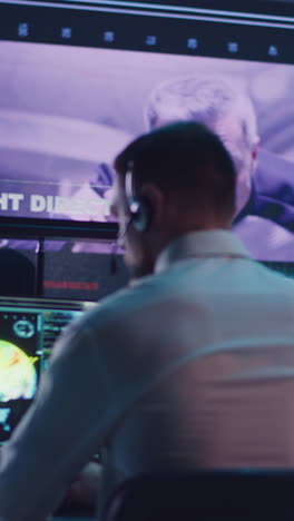 Vertical-shot-of-male-operator-browsing-data-on-computer-while-watching-online-broadcast-with-astronaut-on-orbital-station
