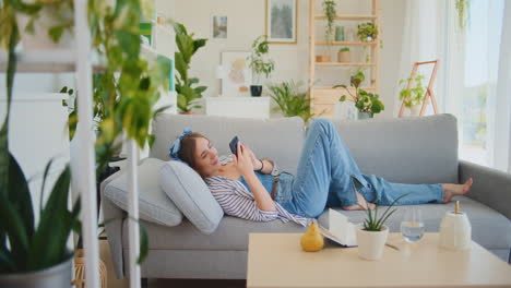 Teenage-Girl-Browsing-Smartphone-on-Sofa