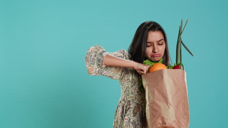 Woman-with-ecological-paper-bag-in-hands-looking-at-bell-pepper,