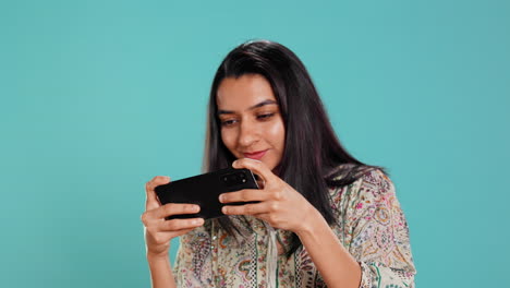Woman-entertained-by-videogames-on-smartphone,-having-fun