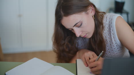 Frau-Schreibt-Hausaufgaben-In-Notizbuch