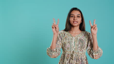 Woman-doing-peace-victory-hand-sign-gesture,-studio-backdrop