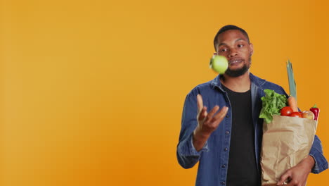Confident-man-juggling-with-an-eco-friendly-green-apple-on-camera