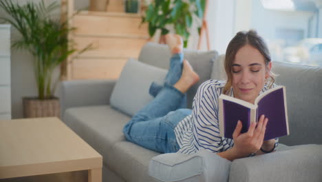 Smiling-Woman-Reading-Favorite-Book-on-Sofa