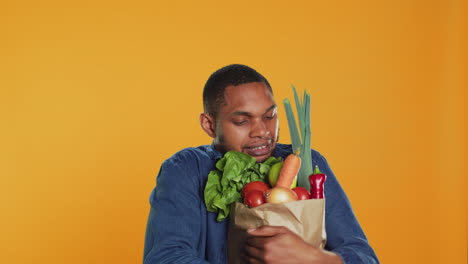 Young-man-struggling-to-carry-a-paper-bag-full-of-fresh-bio-fruits-and-veggies