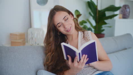 Smiling-Woman-Reading-Book-on-Sofa
