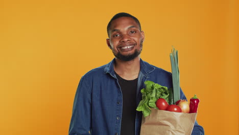 Portrait-of-cheerful-guy-pleased-with-homegrown-groceries-in-a-paper-bag