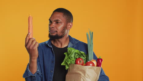 Vegan-guy-looking-closely-at-a-carrot-to-ensure-its-best-shape