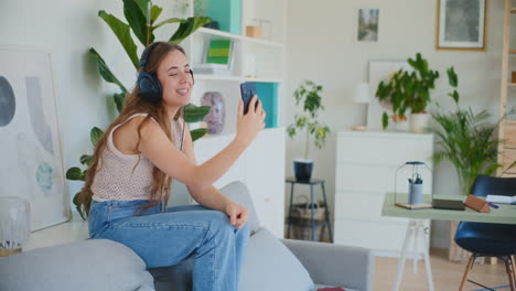 Smiling-Woman-on-Video-Call-with-Friend-While-Sitting-on-Sofa