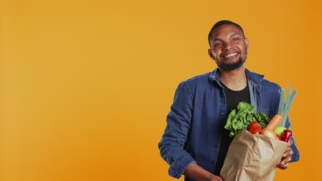 Vegan-adult-presenting-his-ripe-freshly-harvested-produce-in-a-paper-bag
