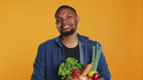 Vegan-adult-presenting-his-ripe-freshly-harvested-produce-in-a-paper-bag
