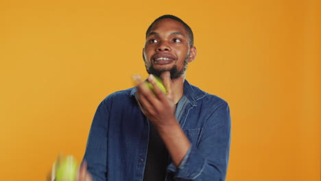 Playful-person-juggling-in-the-studio-with-ripe-green-apples
