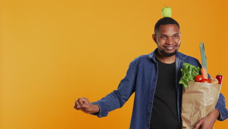 Playful-vegan-guy-dancing-with-an-apple-placed-on-his-head