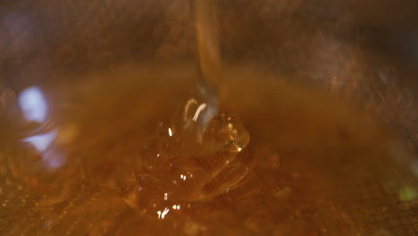 Cone-of-Golden-Honey-Pouring-Through-Sieve