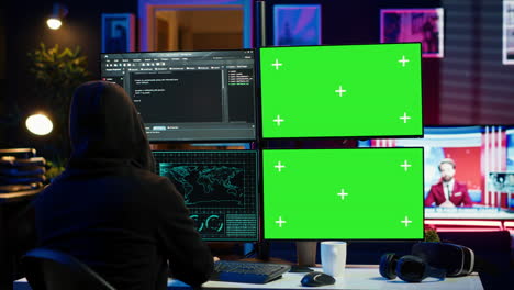 Hooded-man-writing-lines-of-code-on-green-screen-PC-from-apartment