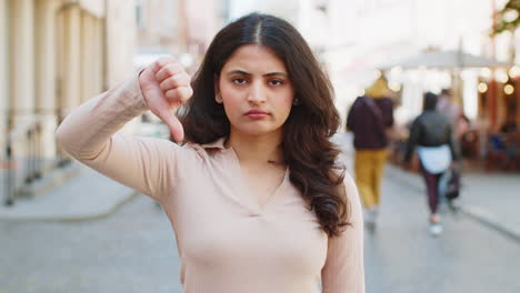 Upset-Indian-woman-showing-thumbs-down-sign,-disapproval,-dissatisfied-bad-work,-mistake-in-city