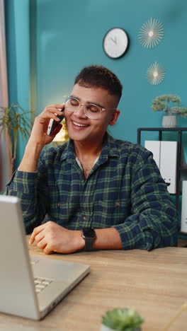 Happy-excited-young-man-making-phone-conversation-call-with-client-or-colleague-sitting-at-home
