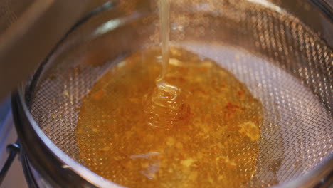 Golden-Honey-with-Caramel-Consistency-Poured-Through-Sieve