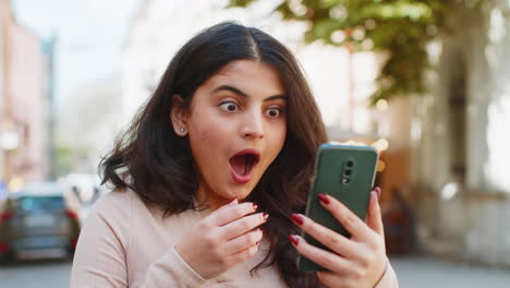 Excited-happy-winner-Indian-woman-use-smartphone-celebrating-win-good-message-news-on-city-street