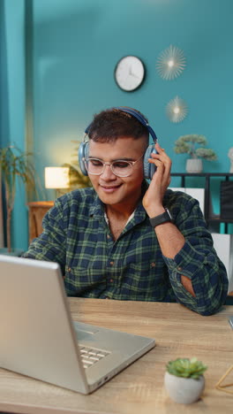 Business-man-listening-music-through-wireless-headphones-relaxing-taking-a-break-laptop-on-table