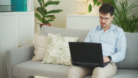 Pensive-Businessman-Working-on-Laptop-While-Sitting-on-Sofa-at-Home