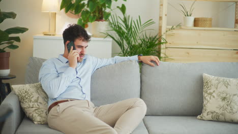 Happy-Man-Talks-on-Phone-Sitting-on-Sofa