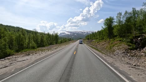 There-is-a-motorhome-travel-RV-with-travelers-on-the-way.-Driving-a-Car-on-a-Road-in-Norway-at-dawn.-Point-of-view-driving.-Family-vacation-travel-RV,-holiday-trip-in-motorhome,-Caravan-car-Vacation.