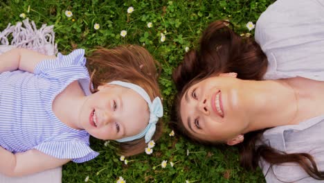 Happy-Mother-with-Baby-Girl-Lying-on-Grass-in-Park.family,-motherhood-and-people-concept-happy-smiling-mother-with-baby-girl-lying-on-grass-in-park
