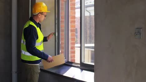 Male-Builder-with-Clipboard-Checking-Window.construction-business-and-building-concept-male-builder-with-clipboard-checking-window