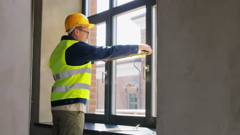 Male-Builder-with-Ruler-Measuring-Window.-construction-business-and-building-concept-male-builder-with-ruler-and-clipboard-measuring-window