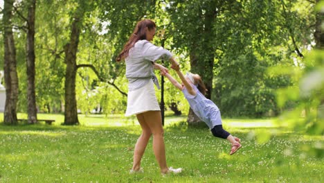 Happy-Mother-with-Little-Daughter-Playing-at-Park.family,-motherhood-and-people-concept-happy-mother-with-little-daughter-playing-at-summer-park-or-garden