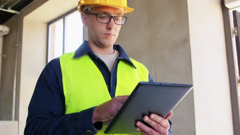Builder-in-Helmet-and-Safety-West-with-Tablet-Pc.architecture,-construction-business-and-building-concept-male-builder-in-helmet-and-safety-west-with-tablet-pc-computer-at-office