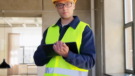 Builder-in-Helmet-and-Safety-West-with-Tablet-Pc.architecture,-construction-business-and-building-concept-male-builder-in-helmet-and-safety-west-with-tablet-pc-computer-at-office