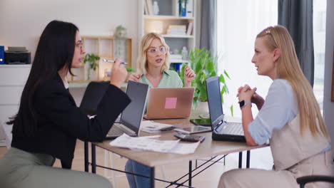 Three-Women-Discuss-Business-Project-During-Meeting