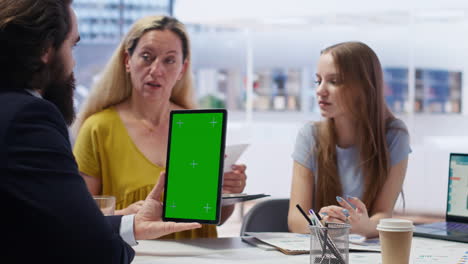 Agent-assisting-clients-in-setting-up-accounts-with-green-screen-tablet