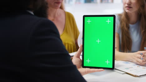 Agent-assisting-clients-in-setting-up-accounts-with-green-screen-tablet
