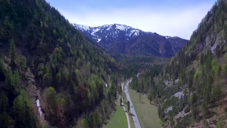 Eine-Drohnenaufnahme-Von-Autos,-Die-Eine-Straße-Entlang-Der-Alpen-Entlangfahren