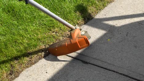 Weed-wacking-the-edge-of-the-grass-beside-the-sidewalk