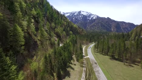 Eine-Drohnenaufnahme-Von-Autos,-Die-Auf-Einer-Straße-An-Den-Alpen-Fahren