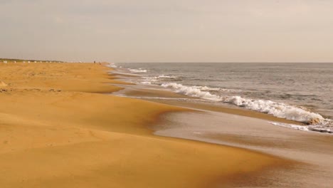 Waves-crashing-on-golden-sand-beach-on-an-overcast-day