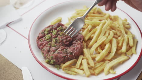 Berühmtes-Französisches-Steak-Tartar-Mit-Pommes-Frites-Gabel,-Das-Mit-Fleisch-Spielt