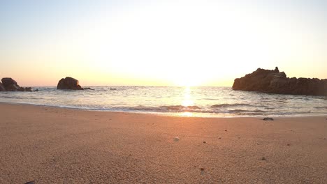 low-Ground-POV,-Calm-ocean-waves-sound-under-warm-sunset-in-Portuguese-beach