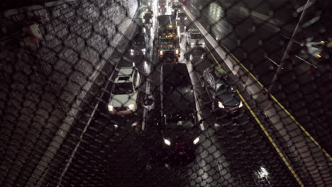 Slow-Traffic-on-Highway-at-Night-Under-Heavy-Rain-Shot-through-Fence