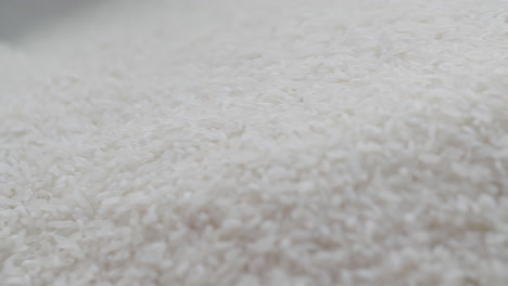Large-amount-of-white-rice-being-hand-shuffled-in-a-mesmerizing-way